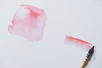 Close-up of red watercolor strokes and a brush on white canvas, showcasing artistic creativity. HD wallpaper