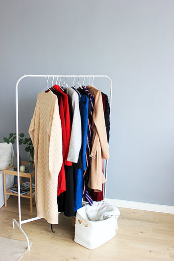 Elegant selection of clothes on a minimalist rack in a modern interior setting. HD phone wallpaper