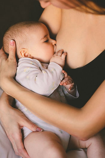 A close-up of a mother lovingly breastfeeding her baby, symbolizing care and motherhood. HD phone wallpaper