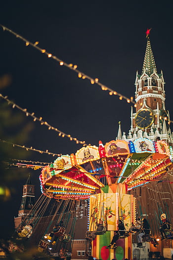 Vibrant carousel in front of the Kremlin at a festive night carnival in Moscow's Red Square. HD phone wallpaper