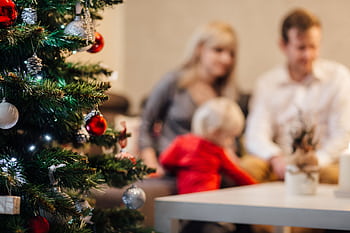 A cozy family gathering by the Christmas tree, enjoying festive decorations. HD wallpaper
