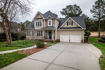 Charming suburban home featuring a two-car garage, manicured lawn, and inviting entrance. HD wallpaper