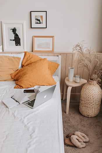 A stylish bedroom setup featuring a laptop, orange pillows, and modern decor. HD phone wallpaper