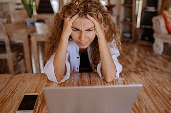 Stressed woman at home struggling with remote work on her laptop. HD wallpaper