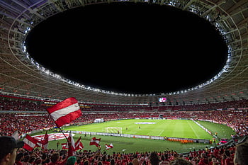 Exciting soccer match with enthusiastic fans in a packed stadium under bright lights. HD wallpaper