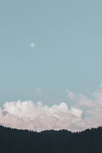 A peaceful scene of clouds and a moon above a forested landscape under a clear blue sky. HD phone wallpaper