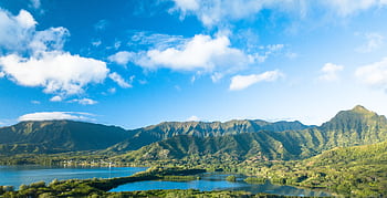 Scenic view of lush mountains and a lake under a bright blue sky with clouds. HD wallpaper