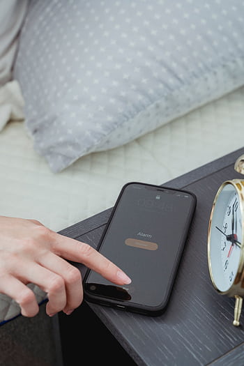 Close-up of a hand turning off an alarm on a smart beside a bed. HD phone wallpaper