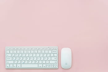 A clean and minimalist flat lay of a white keyboard and mouse on a pastel pink background. Perfect for feminine office themes. HD wallpaper