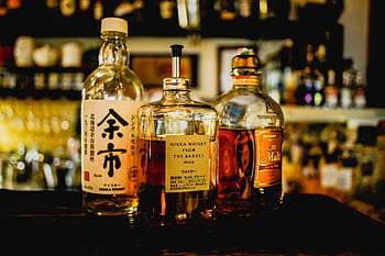 Selection of Japanese whisky bottles displayed in a dimly lit bar setting. HD wallpaper