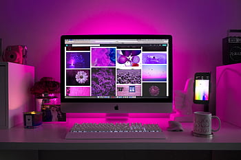 Modern desk setup with neon lighting and a computer displaying colorful . HD wallpaper