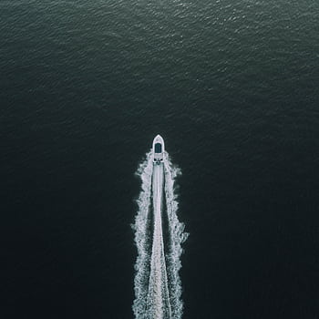 A high-angle shot of a boat creating ripples as it speeds across the tranquil sea, highlighting a peaceful maritime adventure. HD phone wallpaper