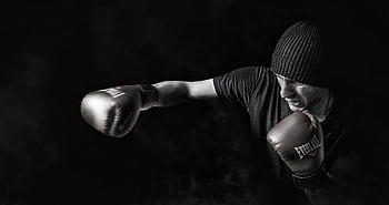 A powerful black and white of a boxer throwing a punch, showcasing strength and focus. HD wallpaper