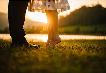 A romantic moment captured at sunset by a tranquil lakeside, showcasing togetherness. HD wallpaper