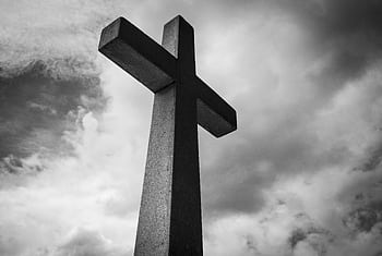A black and white of a cross set against a dramatic, cloudy sky, symbolizing spirituality and faith. HD wallpaper