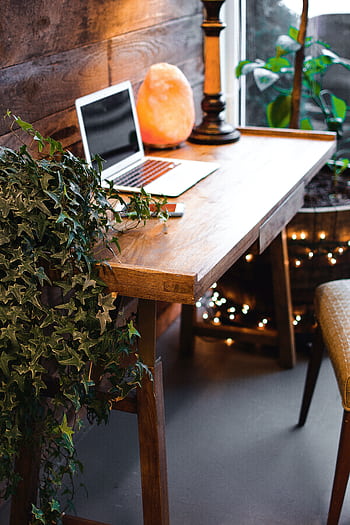 A cozy home office setup featuring a laptop, salt lamp, and plants on a wooden desk. Ideal for remote work. HD phone wallpaper