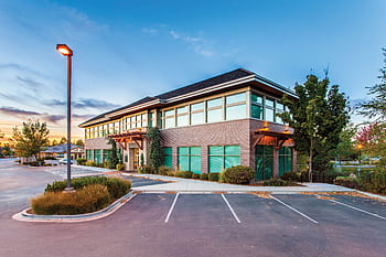 A modern two-story office building in Eagle, ID, captured at sunset with a clear blue sky. HD wallpaper