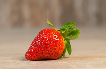 A vibrant close-up of a single, ripe strawberry showcasing freshness and vivid color. HD wallpaper