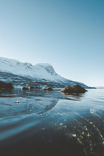 Serene winter landscape featuring frozen lake and snow-covered mountains under a clear sky. HD phone wallpaper