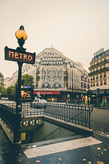 Discover the iconic Galeries Lafayette facade in Paris with nearby metro signs on an overcast day. HD phone wallpaper