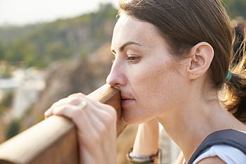 A thoughtful woman leans on a railing, lost in deep contemplation outdoors. HD wallpaper
