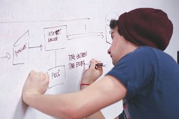 Creative young man working on a strategy plan on a whiteboard at the office. HD wallpaper