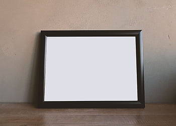 Simple black frame on a wooden table against a plain wall. HD wallpaper