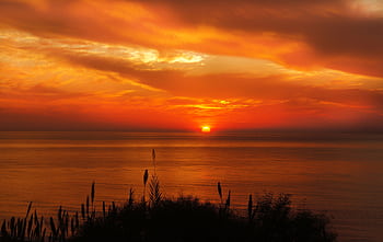 A breathtaking sunset over the ocean with a vivid orange sky and calm waters. HD wallpaper