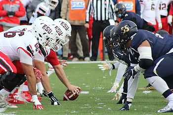 Rival football teams face off at the start of an action-packed game on the field. HD wallpaper