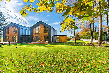 Contemporary wooden houses with lush green lawns surrounded by vibrant autumn foliage. HD wallpaper