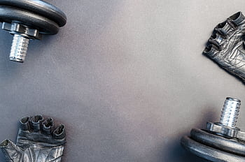 Flat lay of dumbbells and gloves on a workout surface, ready for training. HD wallpaper
