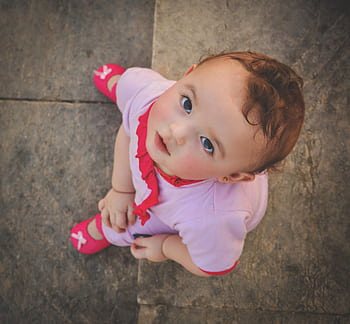 Cute toddler wearing pink, captured from above, gazing up with innocence and curiosity HD wallpaper