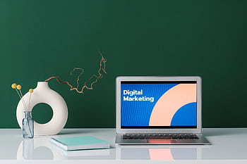 A modern workspace featuring a laptop displaying 'Digital Marketing' against a green wall. HD wallpaper