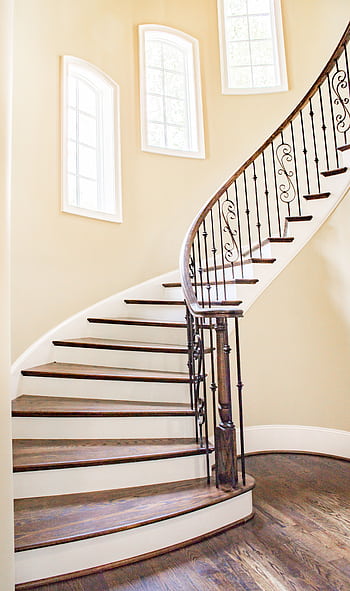Beautiful spiral staircase with iron railings and wooden steps, lit by natural light. HD phone wallpaper