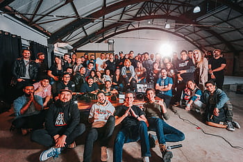 A happy and diverse group posing together in a São Paulo warehouse setting. HD wallpaper