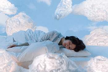 A serene and imaginative portrayal of a woman sleeping surrounded by fluffy clouds. HD wallpaper