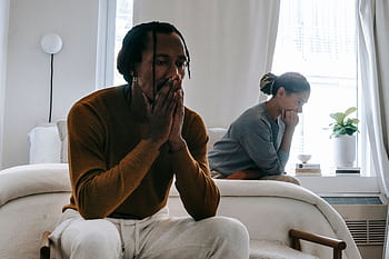 A couple in deep thought and conflict sitting apart in a bedroom. HD wallpaper