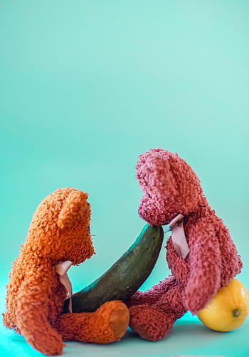 Two colorful teddy bears interacting creatively with fruits and cucumber. HD phone wallpaper