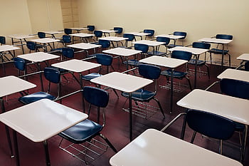 An indoor view of a modern, clean classroom with rows of empty desks and chairs. HD wallpaper