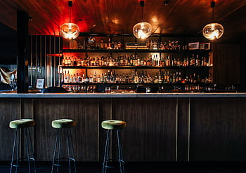 Elegant empty bar counter with stylish lighting and a wide range of beverages on display. HD wallpaper