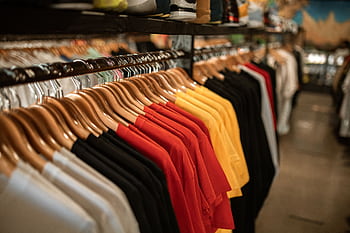 Clothing store display with shirts hanging neatly on a rack indoors. HD wallpaper