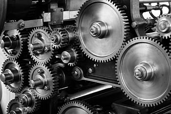 Close-up view of a complex industrial gear mechanism in black and white. HD wallpaper