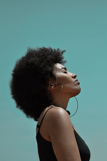 Profile of a stylish young woman with Afro hair, eyes closed, embracing sunlight. HD phone wallpaper