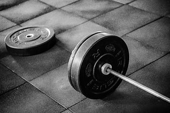 Grayscale of heavy gym barbell and weights on rubber mat flooring. HD wallpaper