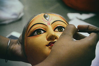 Artisan painting a traditional Durga idol mask for the Durga Puja festival. HD wallpaper