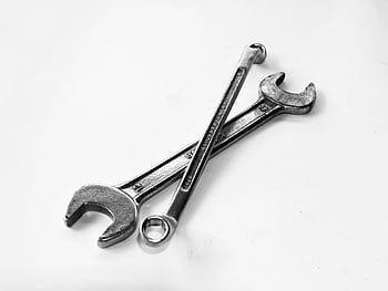 A pair of crossed metal wrenches on a clean white surface. HD wallpaper