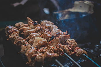Delicious grilled skewers sizzling on a charcoal grill with smoke and juicy texture. HD wallpaper