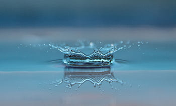 Macro shot of a water droplet creating a ripple effect on the water surface. HD wallpaper
