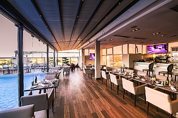 Spacious modern restaurant interior with a poolside view, featuring elegant furniture and contemporary design. HD wallpaper