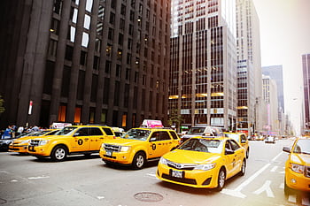 Street scene with yellow taxis in New York City, iconic urban traffic captured in daylight. HD wallpaper